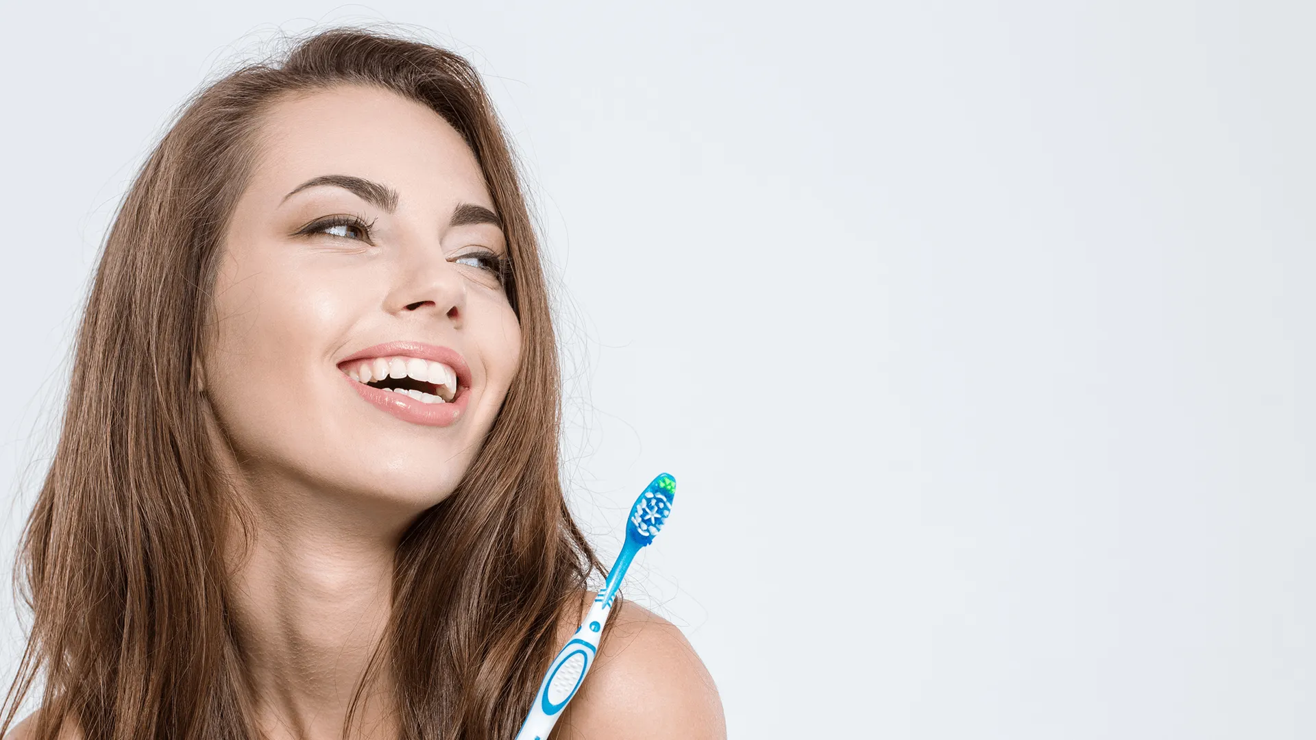 An image of a smiling lady holding a toothbrush 