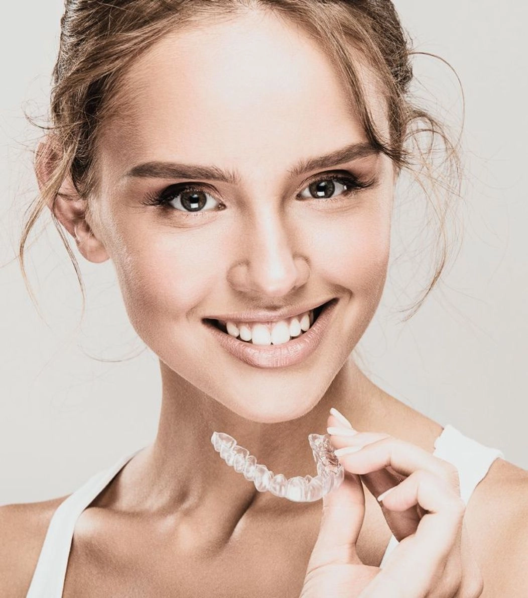 An image of a lady holding Invisalign aligners