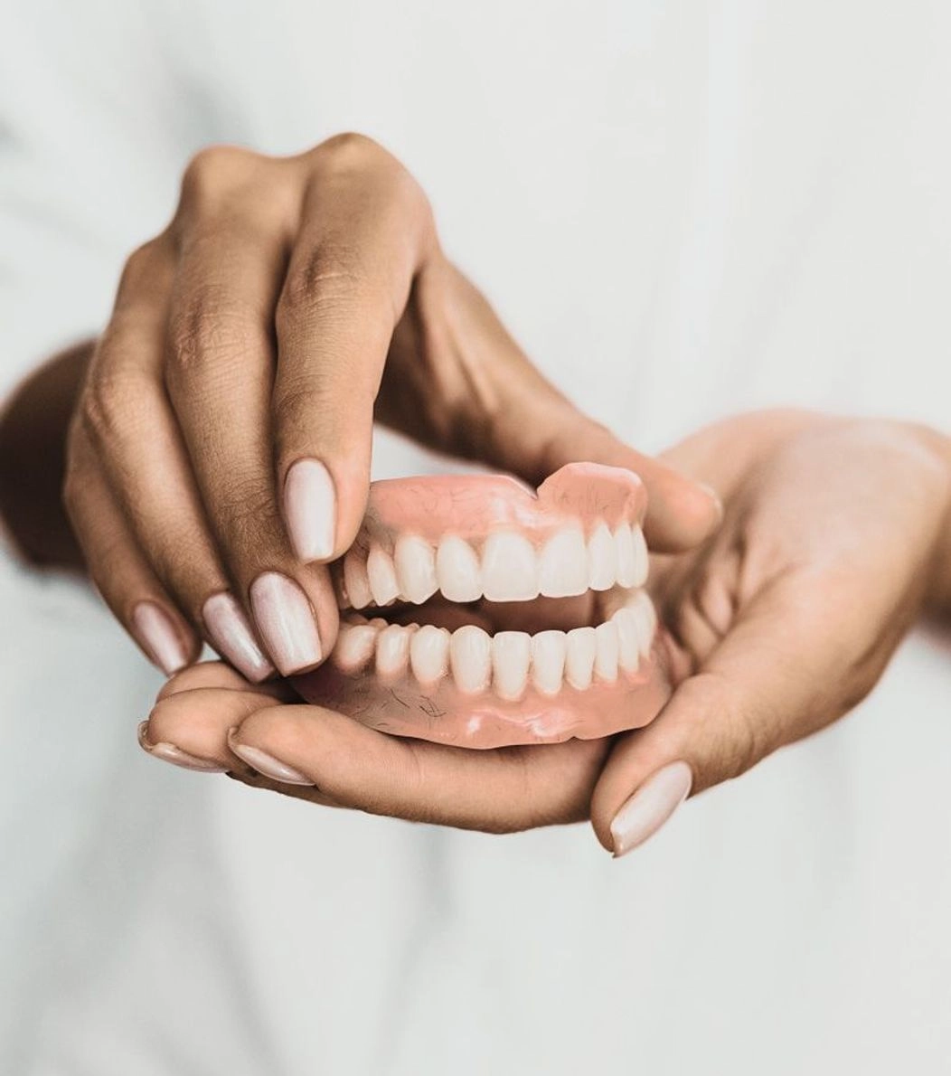 An image of complete dentures being held