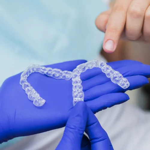 Gloved hand holding two clear aligners.