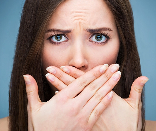 Worried woman with hands covering her mouth