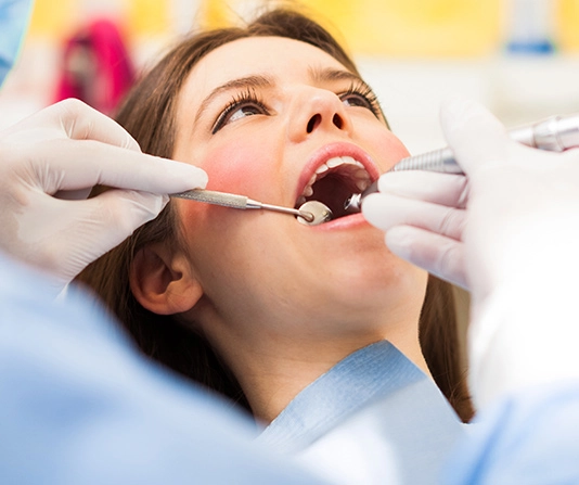 Dental oral exam for woman in chair, dentists hands are in view