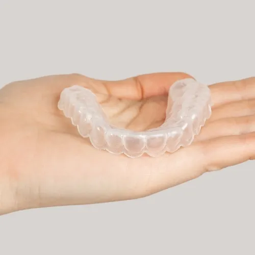 Clear aligner in the palm of a hand.