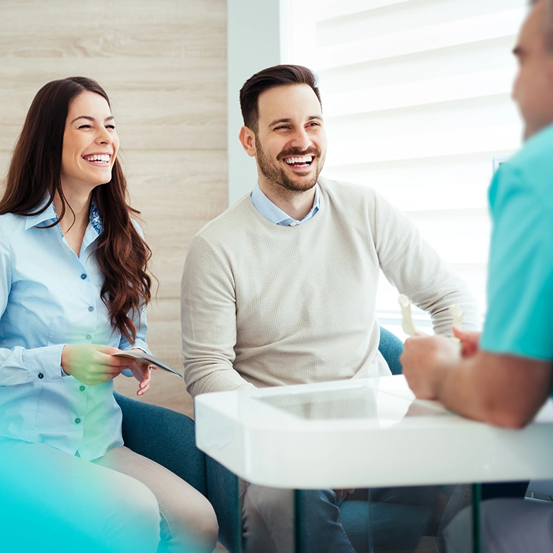 An image of a couple laughing with their dentist