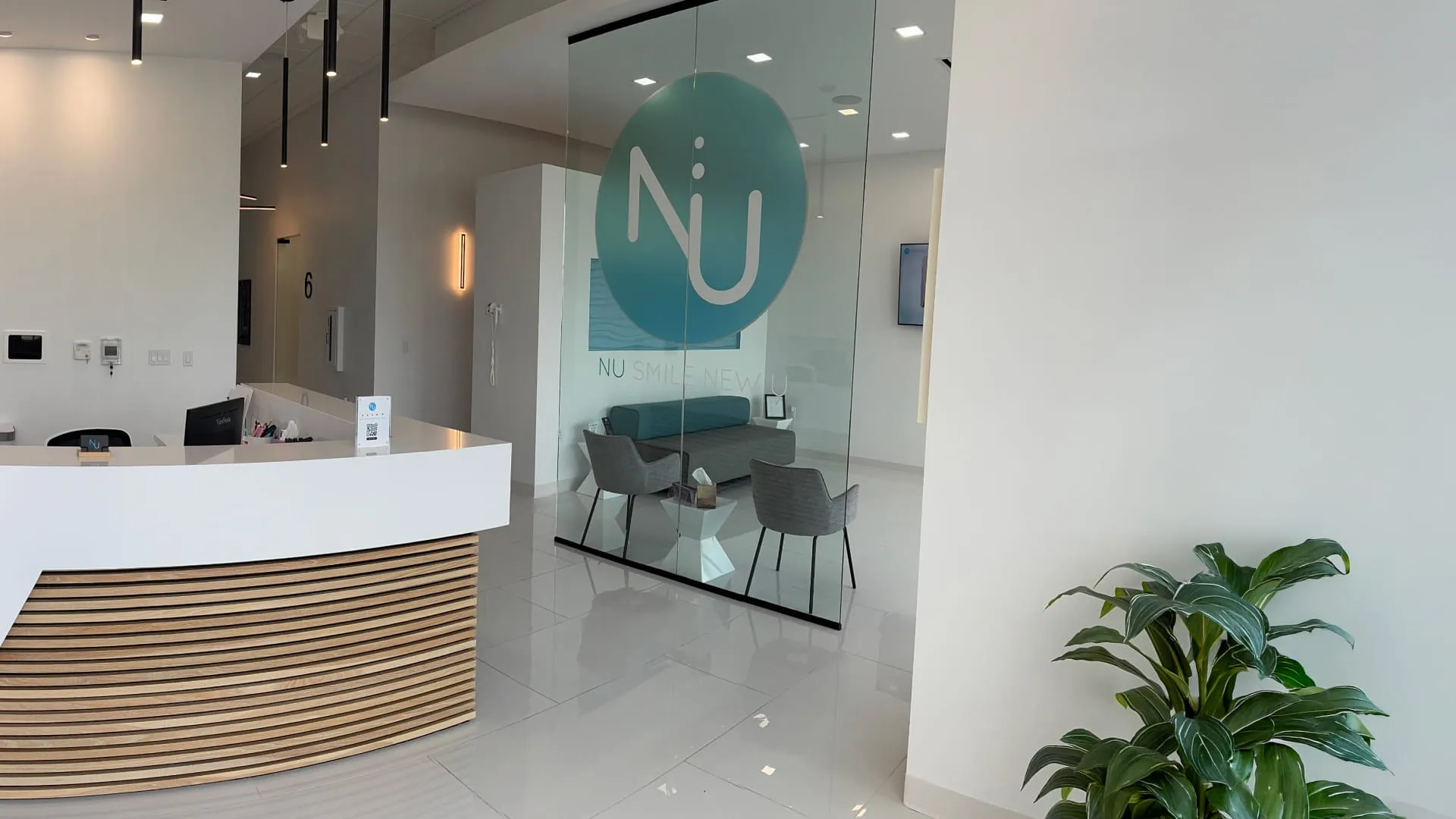 Nu Dentistry reception desk with wood slat detail and branded glass waiting room partition